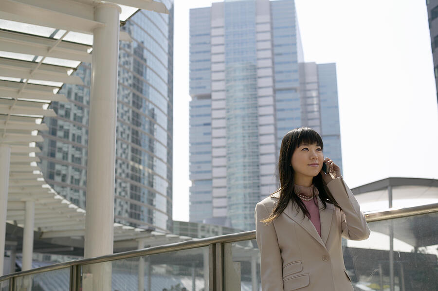 Businesswoman Using a Mobile Phone, with Office Blocks in the Background Photograph by Digital Vision.
