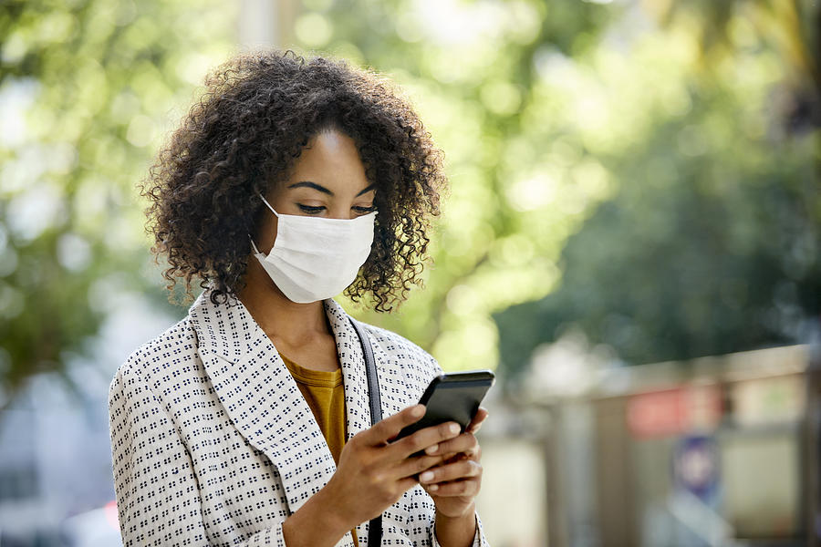 Businesswoman using smart phone during COVID-19 pandemic in city, She is Wearing Protective Face Mask Photograph by Morsa Images