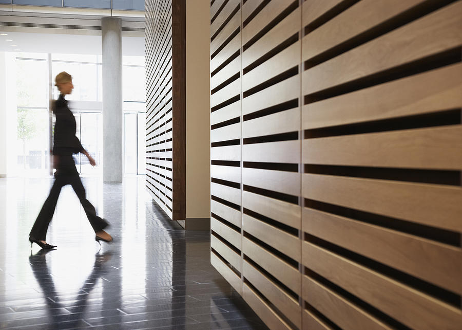 Businesswoman walking in corridor Photograph by Martin Barraud