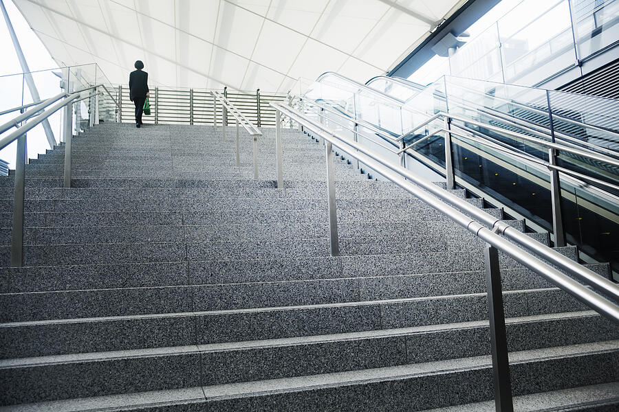 Businesswoman walking up stairs Photograph by Hiroshi Watanabe