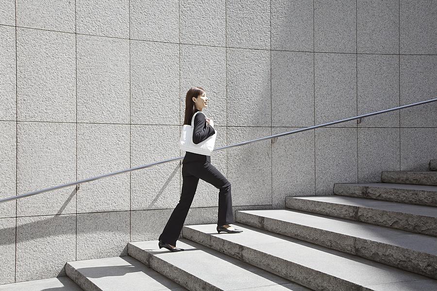 Businesswoman walking up steps Photograph by Image Source