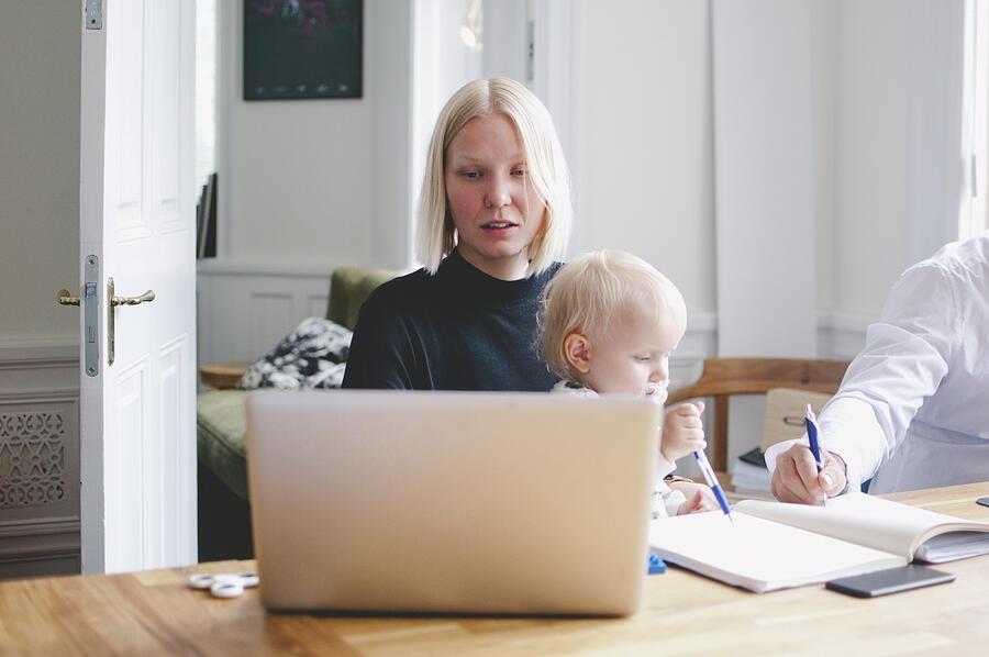Businesswoman with baby girl using laptop at table in creative office Photograph by Maskot