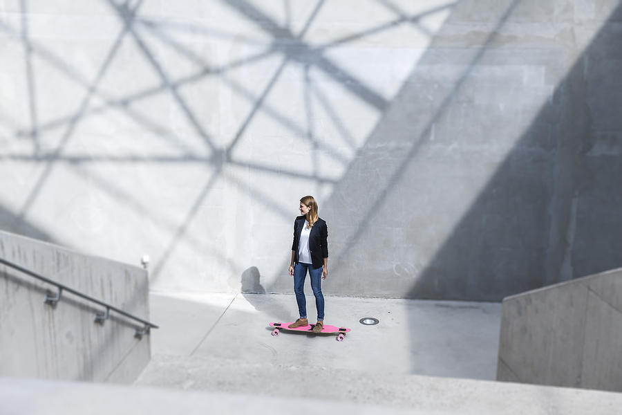 Businesswoman with pink skateboard in modern architecture Photograph by Westend61