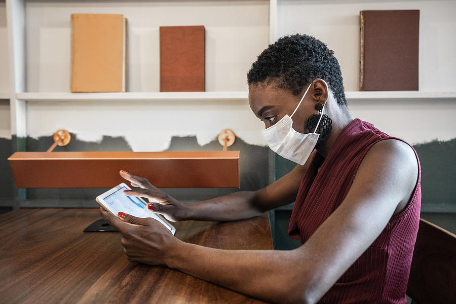 Businesswoman working with mask using digital tablet at work Photograph by FG Trade