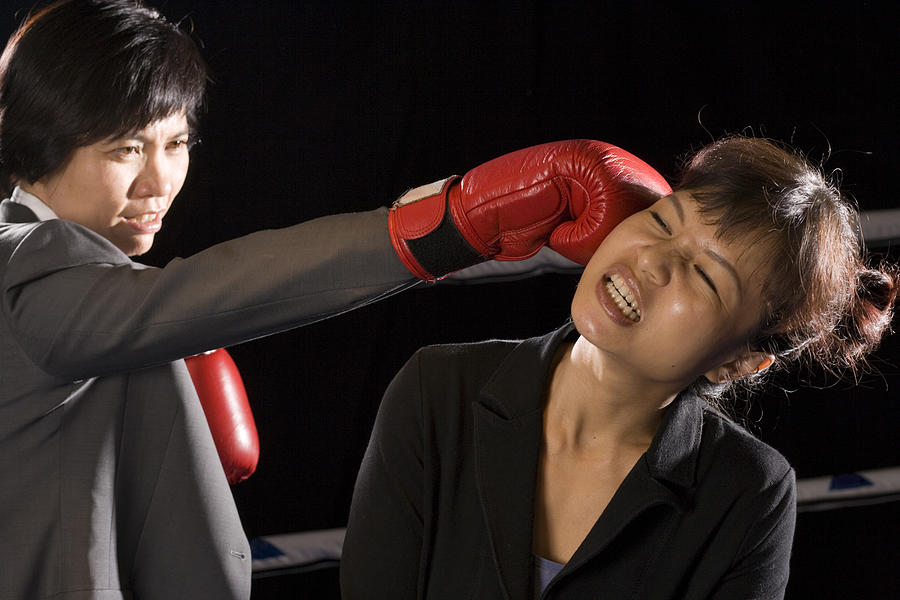 Businesswomen being hit by her opponent in a boxing ring Photograph by Asiaselects