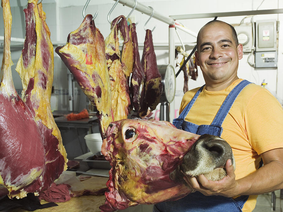 Butcher holding slaughtered cows head Photograph by Hans Neleman