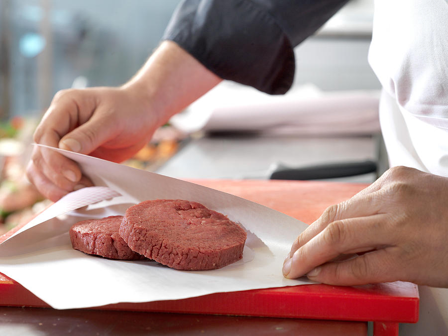 Butcher wrapping beef patties in wax paper, cropped Photograph by PhotoAlto/Thierry Foulon