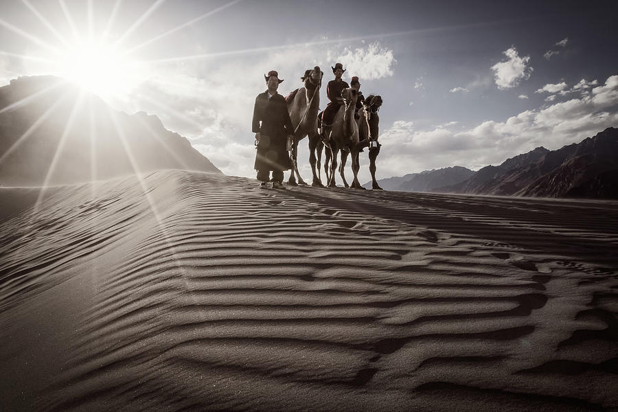 Camel riders on the crest of a sand dune in the Nubra Valley Photograph by Murray Rudd