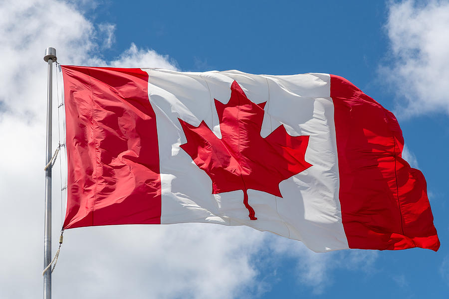 Canada flag waving on a blue sky Photograph by Roberto Machado Noa