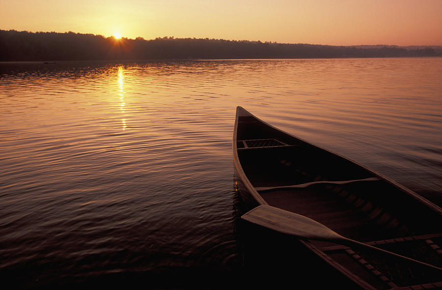 Canoe on a lake at sunset Photograph by Scott Barrow