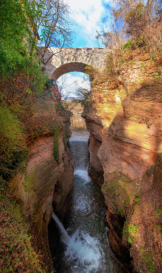 Nature Photograph - canyon with rock bridge colorful beautiful orange without people with clear blue sky vertical background Ravine Orrido of Ponte Alto in Trento - region Trentino Italy by Luca Lorenzelli