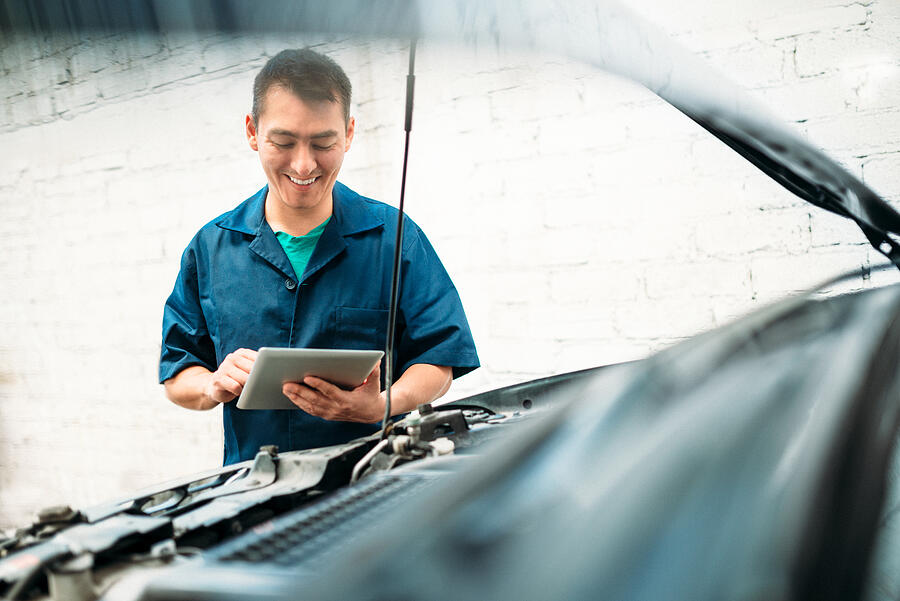 Car mechanic filling repair check list on tablet Photograph by Ferrantraite