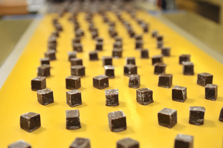 Caramels on a conveyor belt Photograph by Nano