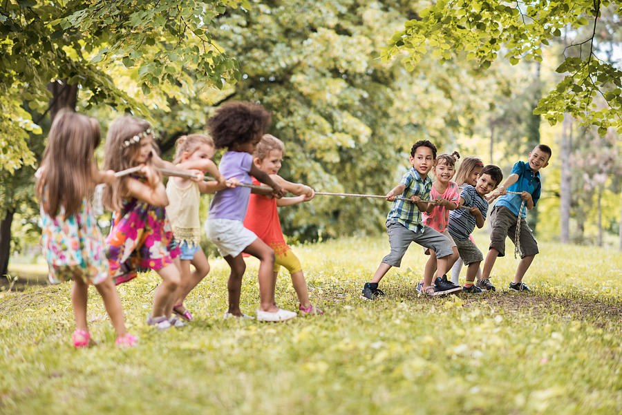 Carefree kids having fun while playing tug-of-war in nature. Photograph by BraunS