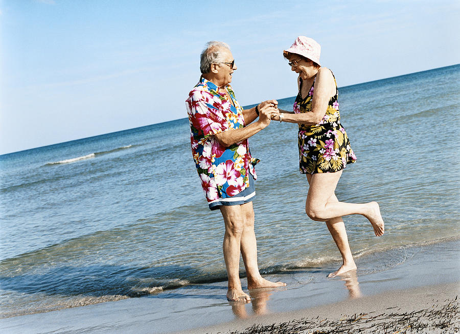 Carefree Senior Couple Dance on the Beach at the Waters Edge Photograph by Digital Vision.