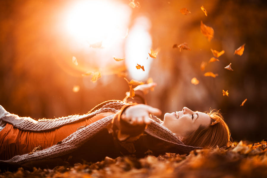 Carefree woman relaxing and throwing autumn leaves in nature. Photograph by BraunS