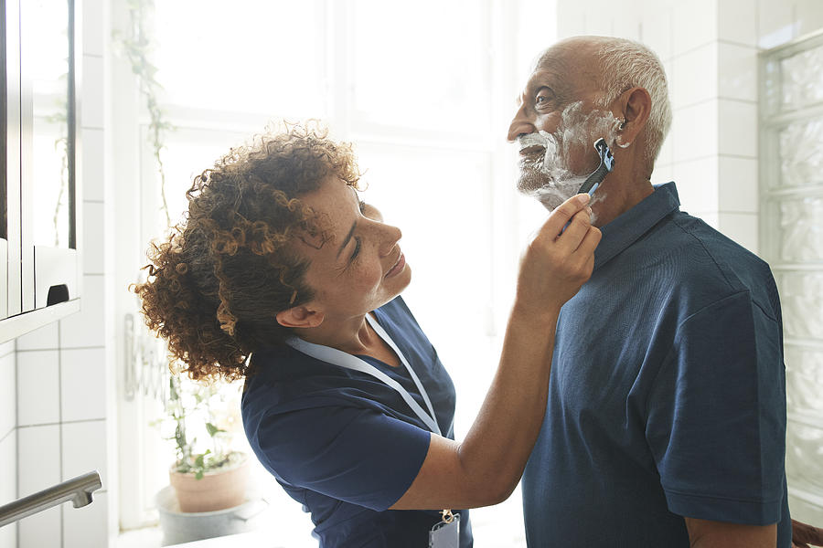 Caregiver helping retired senior man in shaving Photograph by Klaus Vedfelt