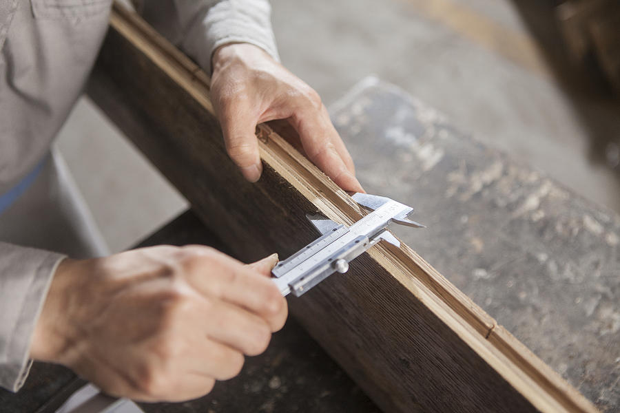Carpenter measuring wood plank with vernier caliper in factory, Jiangsu, China Photograph by Philippe Roy