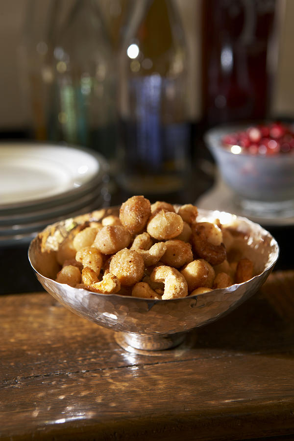 Cashew nuts and macadamia nuts in bowl on table, close-up Photograph by Maren Caruso