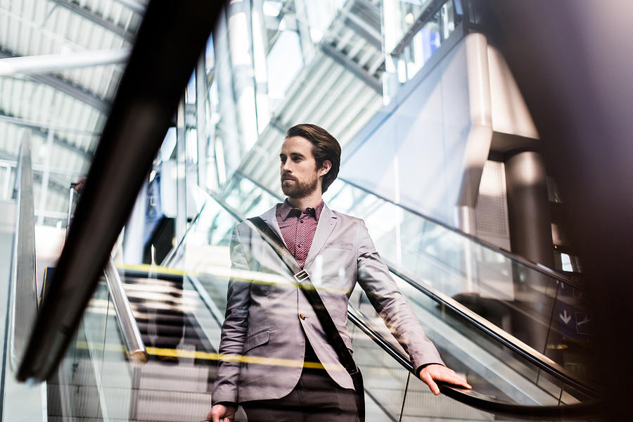 Casual Businessman On Escalator At Airport Photograph by Hinterhaus Productions