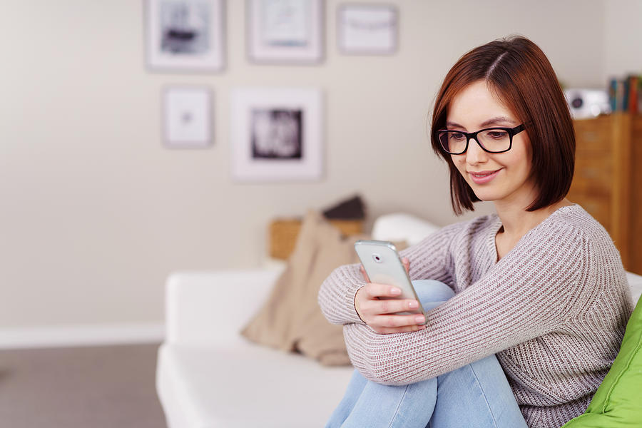 Casual young woman reading a text message Photograph by Stockfour