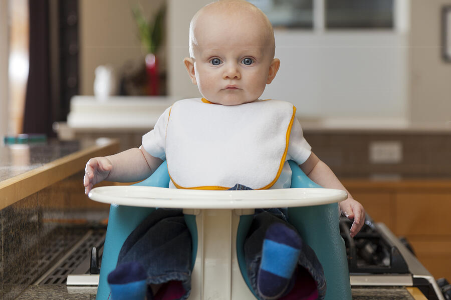 Caucasian baby sitting in high chair Photograph by John Lee