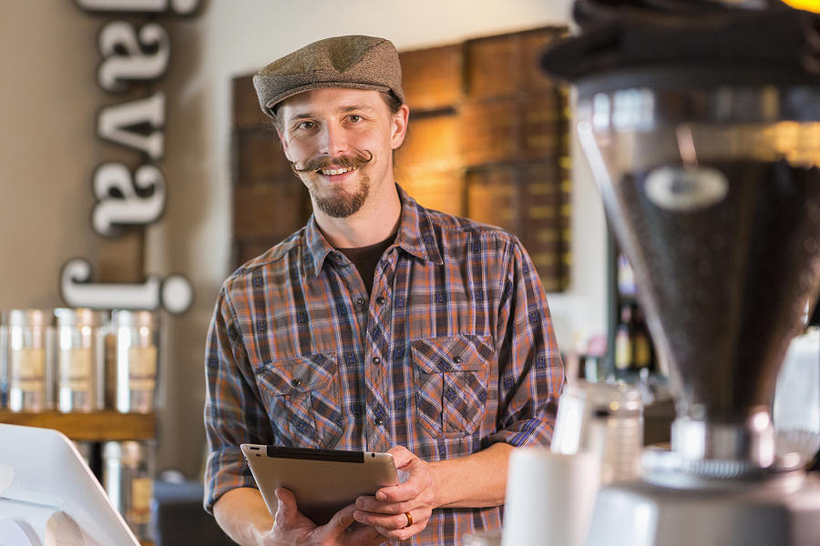 Caucasian barista holding digital tablet in cafe Photograph by Marc Romanelli