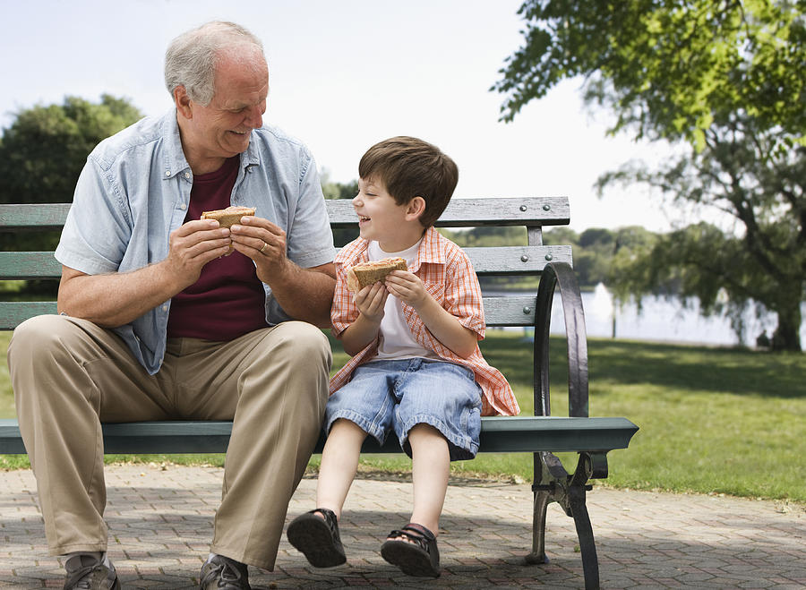 Caucasian boy and grandfather eating in park Photograph by Jose Luis Pelaez Inc