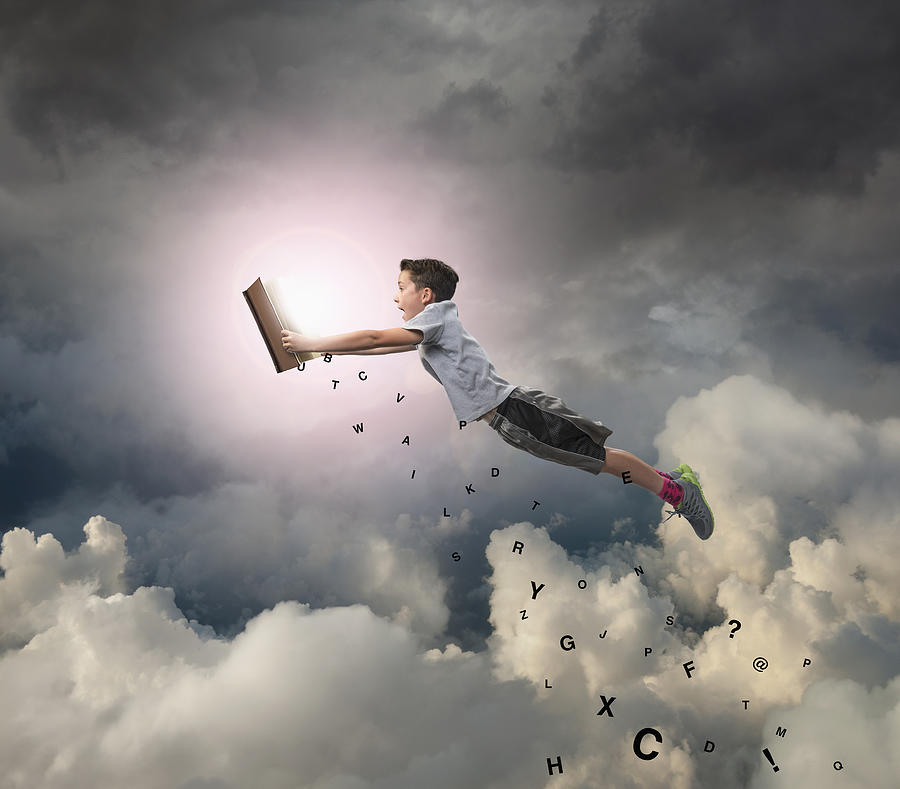 Caucasian boy flying with book in sky Photograph by John M Lund Photography Inc