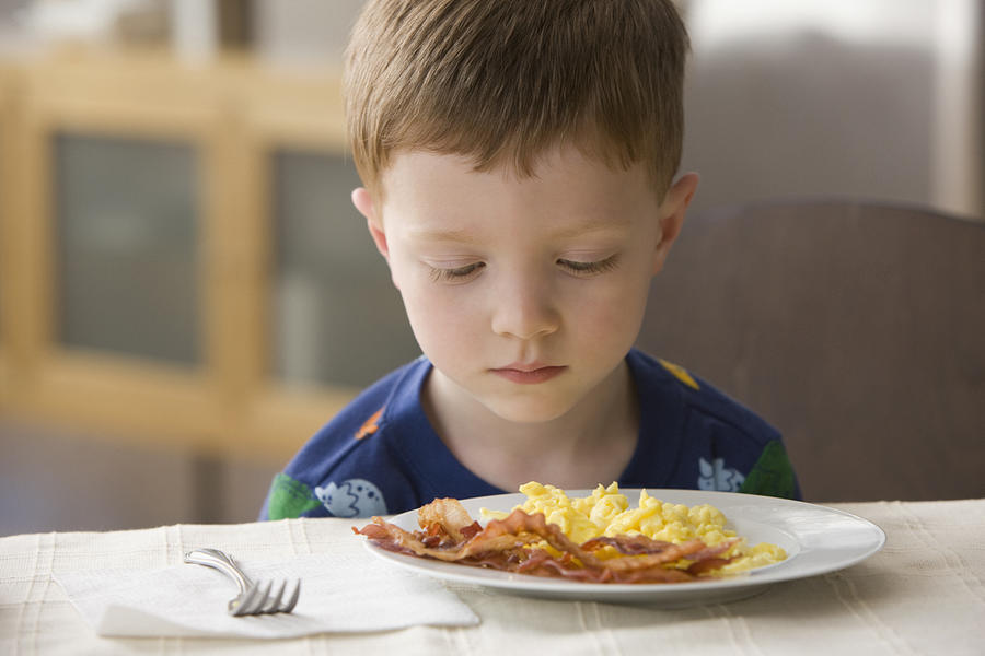 Caucasian boy looking at plate of eggs and bacon Photograph by Jose Luis Pelaez Inc