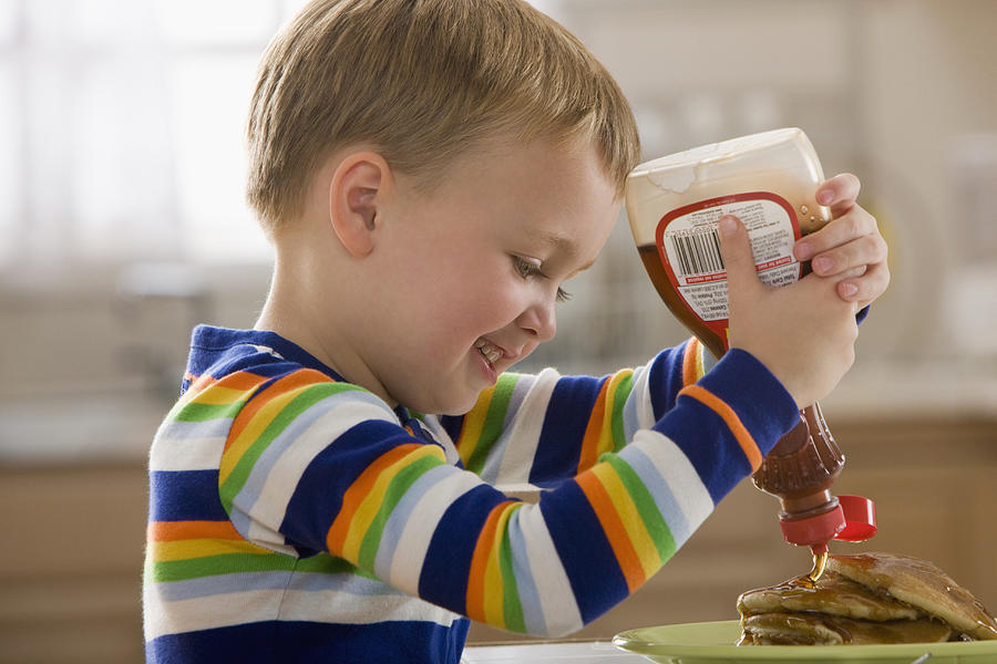 Caucasian boy pouring syrup on pancakes Photograph by Jose Luis Pelaez Inc
