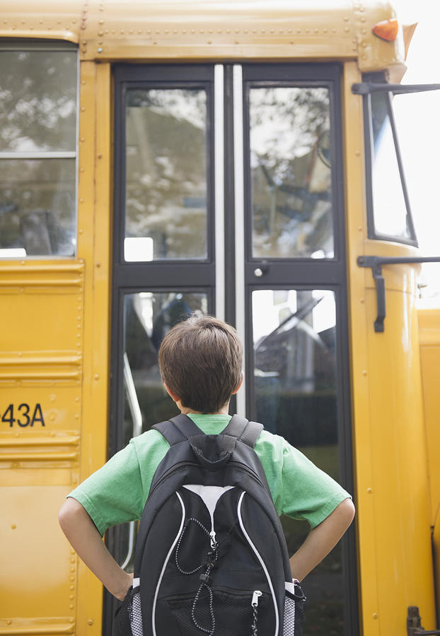 Caucasian boy waiting for school bus Photograph by JGI/Jamie Grill