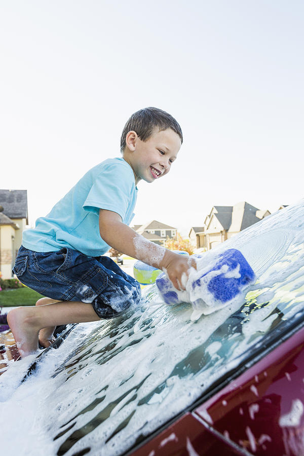 Caucasian boy washing car windshield Photograph by Mike Kemp