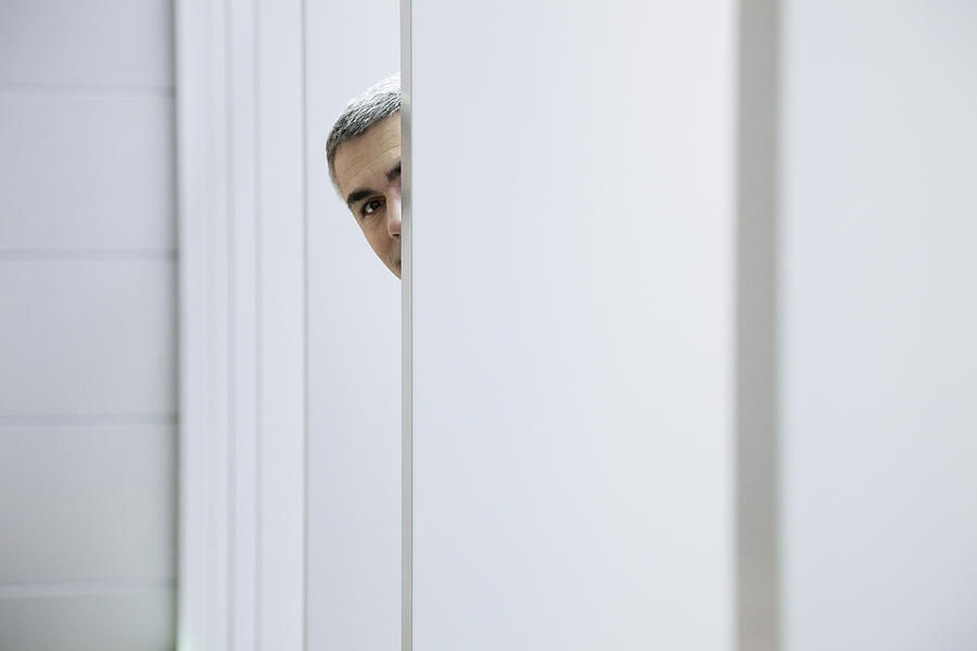 Caucasian businessman peering around wall Photograph by Jetta Productions Inc