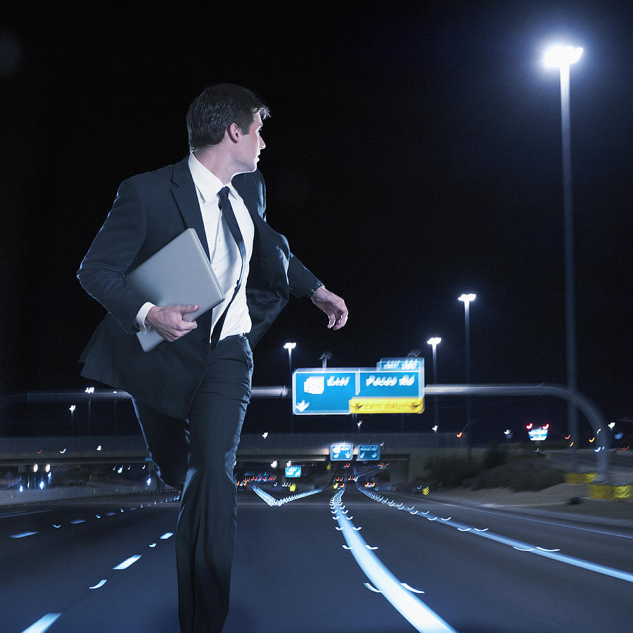 Caucasian businessman running on urban freeway at night Photograph by Jacobs Stock Photography Ltd