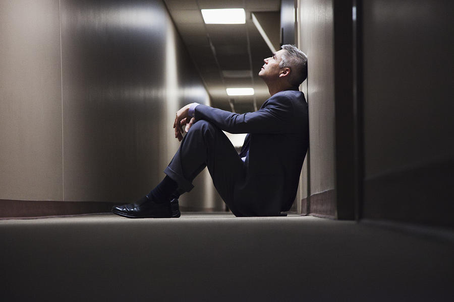 Caucasian businessman sitting on floor in corridor Photograph by Jetta Productions Inc