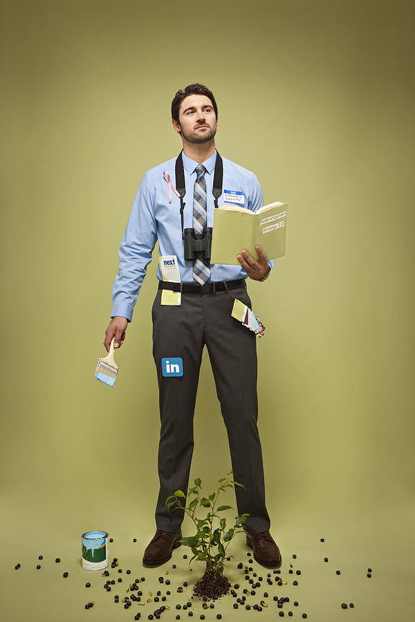 Caucasian businessman with book, pot of paint, plant and binoculars Photograph by Kyle Monk