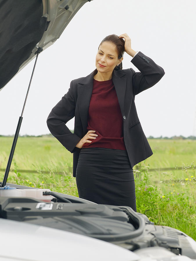 Caucasian businesswoman examining broken-down car on rural road Photograph by Jacobs Stock Photography Ltd
