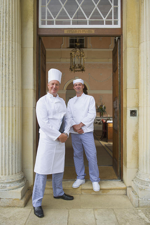 Caucasian chefs standing in mansion front door Photograph by Jacobs Stock Photography Ltd