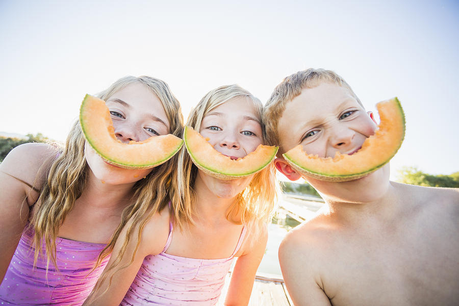 Caucasian children eating cantaloupe slices Photograph by Mike Kemp