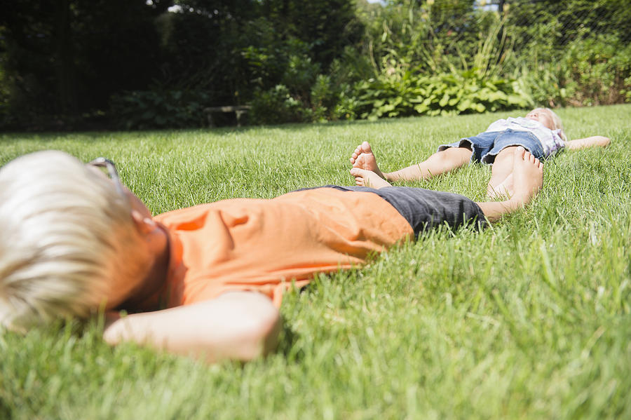 Caucasian children laying on lawn in backyard Photograph by JGI/Jamie Grill