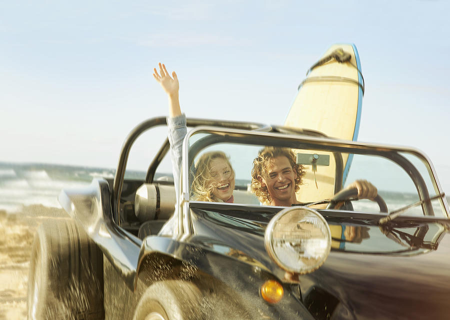 Caucasian couple driving jeep on beach Photograph by Colin Anderson Productions pty ltd
