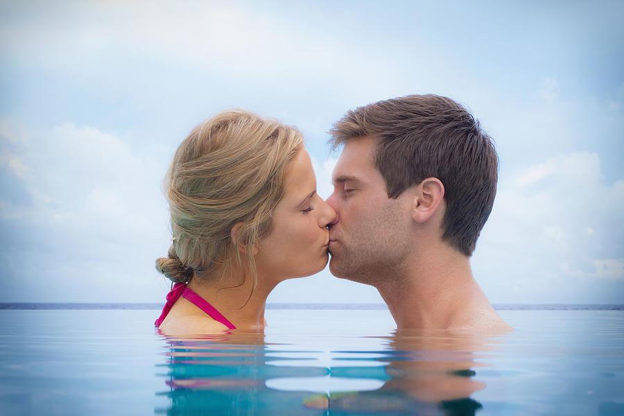 Caucasian couple kissing in swimming pool Photograph by Jacobs Stock Photography Ltd