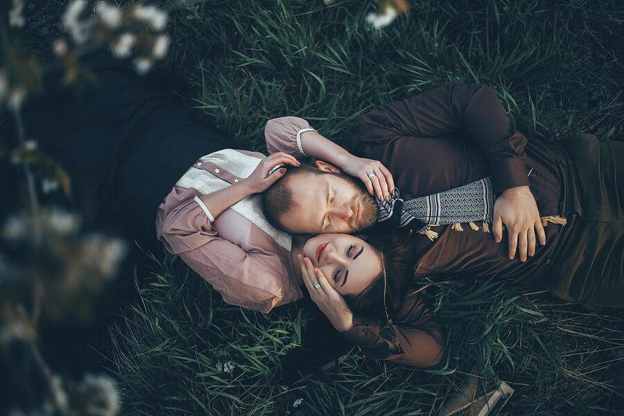 Caucasian couple laying in grass cheek to cheek Photograph by Kateryna Soroka