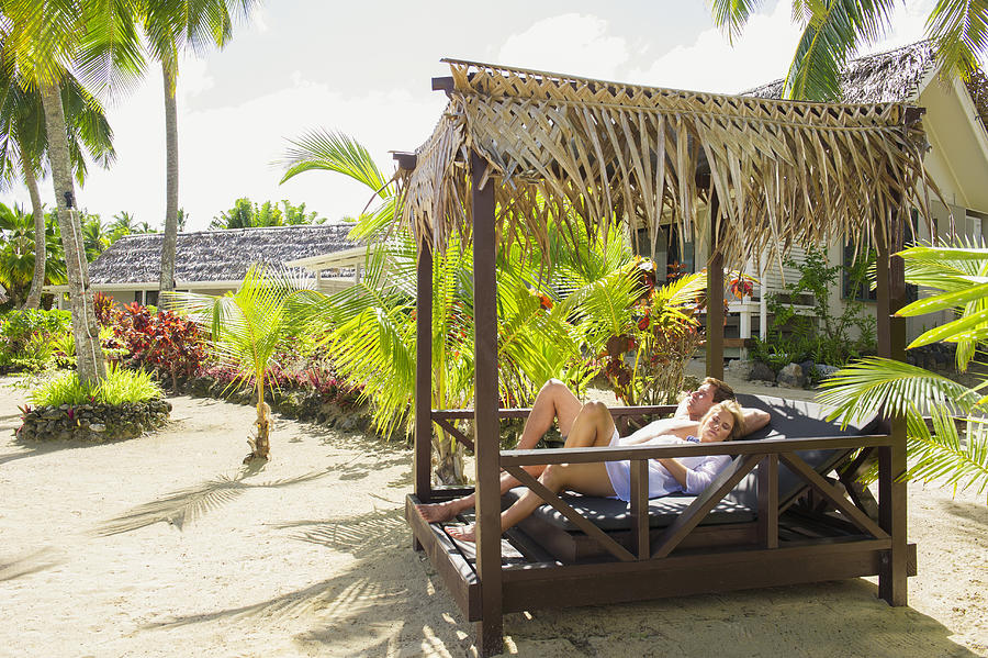 Caucasian couple relaxing in cabana on tropical beach Photograph by Jacobs Stock Photography Ltd