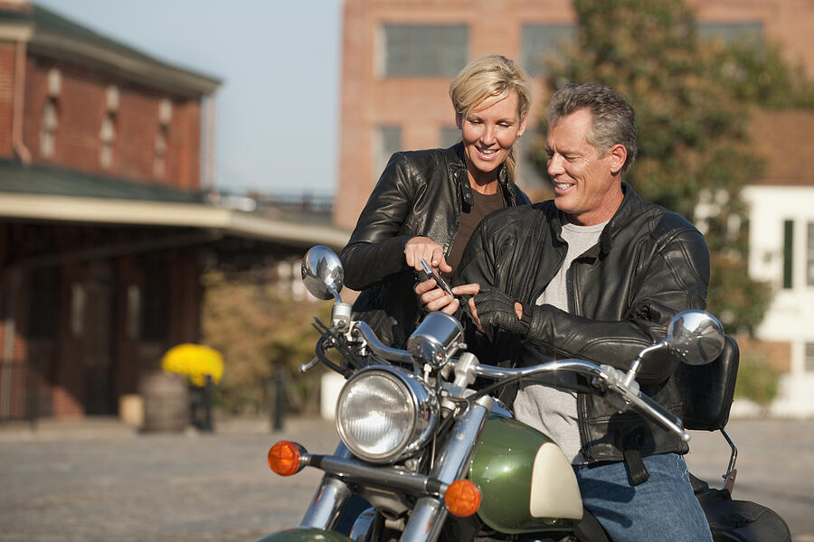 Caucasian couple sitting on motorcycle Photograph by Ariel Skelley