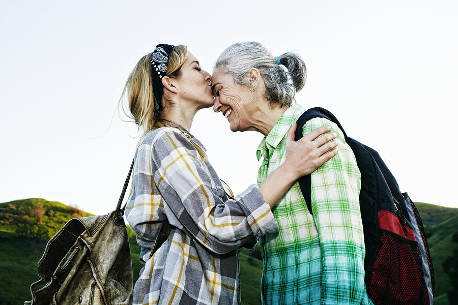 Caucasian daughter kissing mother on rural hilltop Photograph by Peathegee Inc