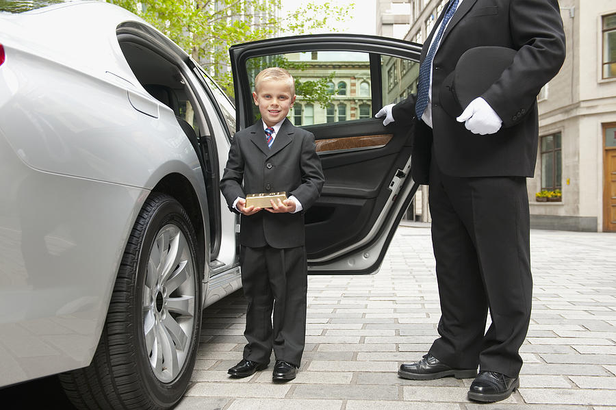 Caucasian driver opening car door for businessman boy Photograph by Jacobs Stock Photography Ltd
