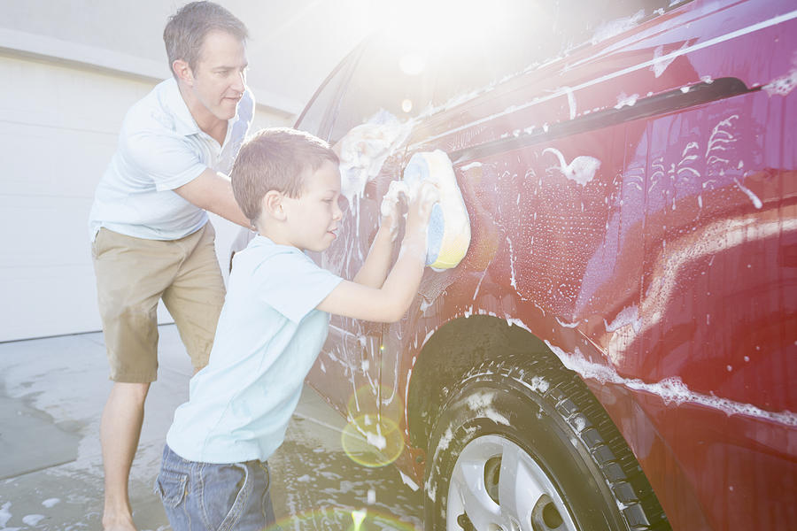 Caucasian father and son washing car in driveway Photograph by Mike Kemp