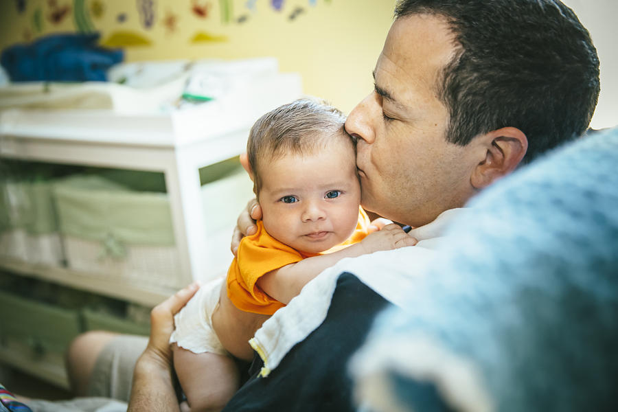Caucasian father kissing baby boy in nursery Photograph by Inti St Clair